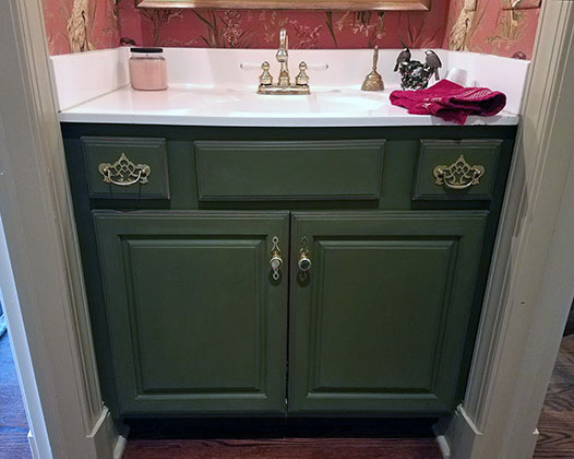 Bathroom vanity with green cabinets.