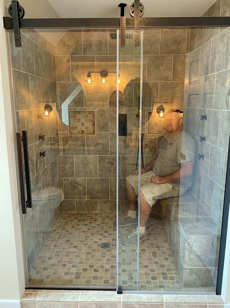Company owner Chuck Foskey sits in a recently renovated shower with a smile.