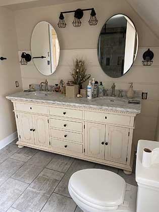 A double sink arrangement with white cabinets and a granite countertop.
