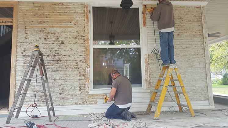 Image of a historic home in Cambridge being renovated.  The paint is being removed from the first floor exterior.