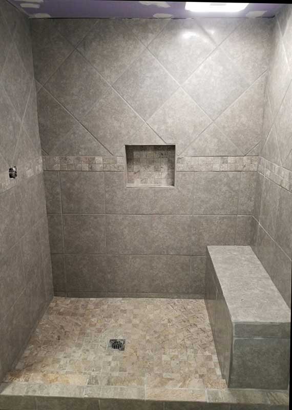 An off-white shower with bench seat and recessed storage.